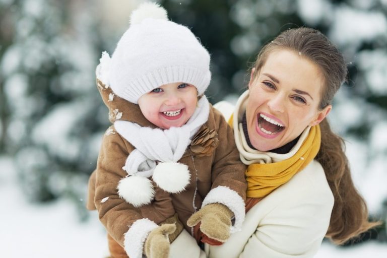 Woman and child smiling in snow.