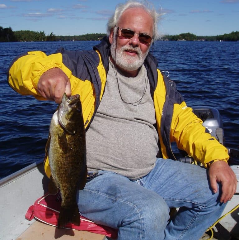 A proud angler single-handedly hoists a plump smallmouth bass while fishing in Ontario.