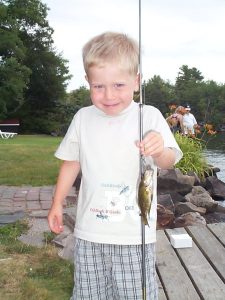 A young angler smiles while holding a small rock bass, just one of many species found in Gloucester Pool.