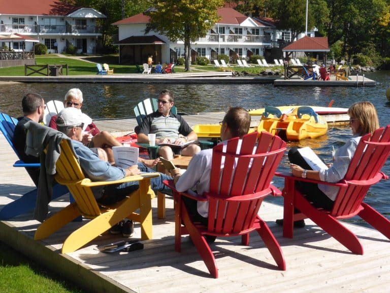 Corporate group having meeting on the pier in Adirondack chairs.