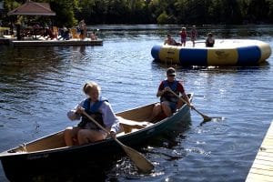 Two people in canoe. Kids on lily pad water trampoline.