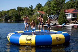 Photo of a Group of Teen Boys Bouncing on a Water Trampoline. Click Here for 30 Things to Do in Muskoka with Kids.