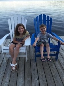 Two children sit in Muskoka chairs as they await their next fun summer activity for kids.