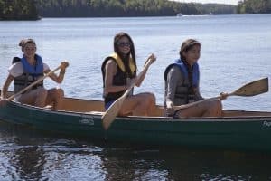 A group of adolescent girls paddle a canoe, one of many summer activities for kids at Severn Lodge.