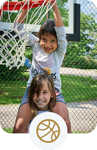 Two girls smiling under a basketball hoop