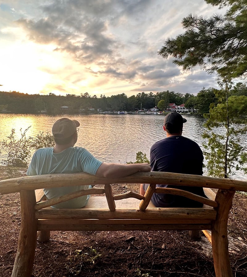 Friends relaxing on a lakeside wooden bench