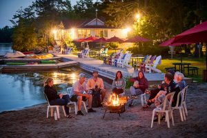 Corporate Retreats Ontario: A group of coworkers gather around a bonfire at night to discuss teambuilding.