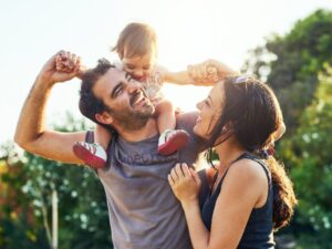 Muskoka Family Resorts: A mother and father gleefully enjoy their young child's reaction to riding on her dad's shoulders.